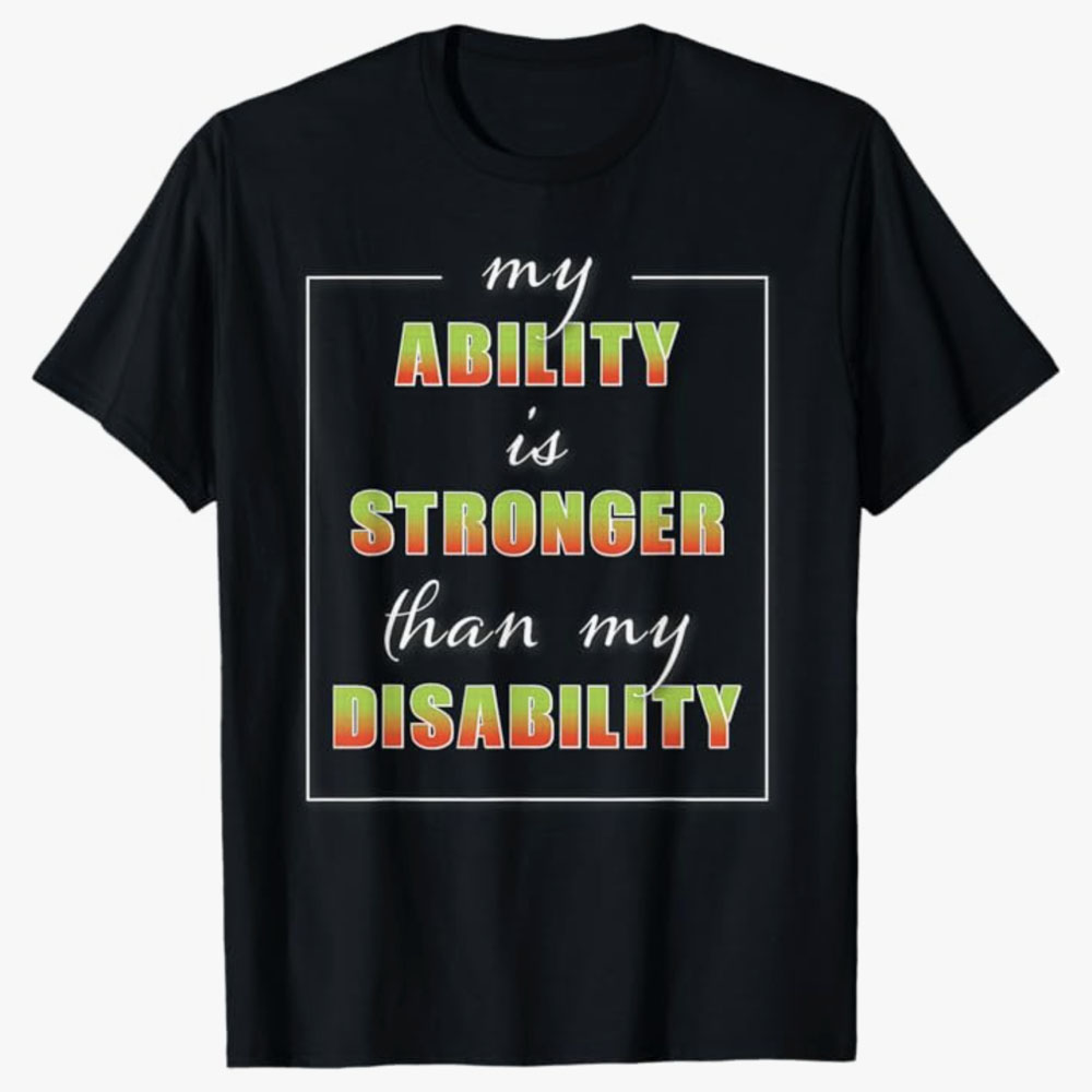 A black T-shirt displays the message “My ability is stronger than my disability” in bold, colorful lettering framed by a simple border. The design promotes empowerment, self-confidence, and a focus on strengths over limitations.