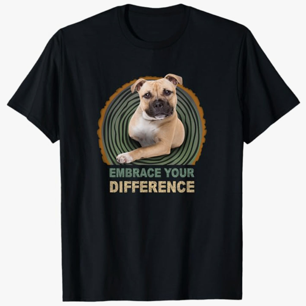 Black T-shirt featuring a dog with a missing leg and the text Embrace Your Difference, spreading a message of resilience, acceptance, and pride in uniqueness through a heartwarming design.