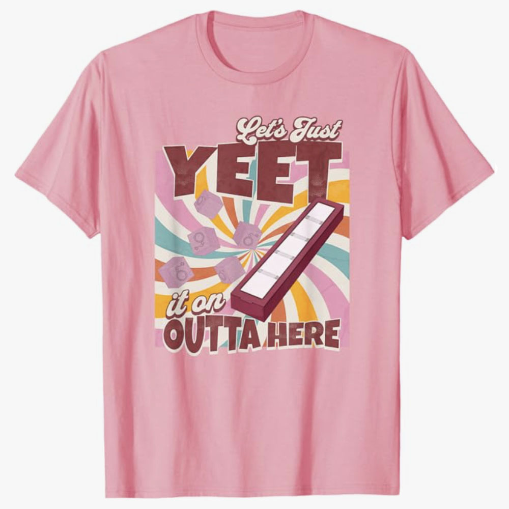 A pink T-shirt features the playful phrase Let’s Just Yeet It on Outta Here above a retro swirl background with tossed blocks and a launcher graphic. The design expresses a humorous, carefree attitude about getting rid of something with dramatic flair.