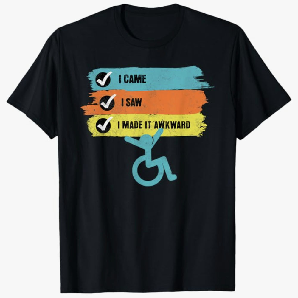 A black T-shirt features a checklist reading I came, I saw, I made it awkward in colorful brushstroke bars, with a playful wheelchair icon below. The design uses humor to celebrate confidence, disability pride, and embracing awkward moments.