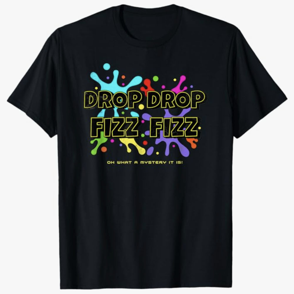 A black T-shirt displays the bold phrase Drop Drop Fizz Fizz over colorful splash graphics, with the caption Oh What a Mystery It Is below. The design conveys playful excitement and fun tied to the surprise of a fizzy reveal.