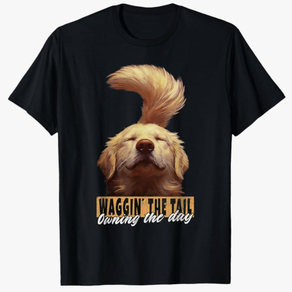 A black T-shirt features a joyful golden retriever with its tail curved high above its head, paired with the phrase Waggin’ the Tail Owning the Day. The design expresses happiness, positivity, and the carefree spirit of a lovable dog.