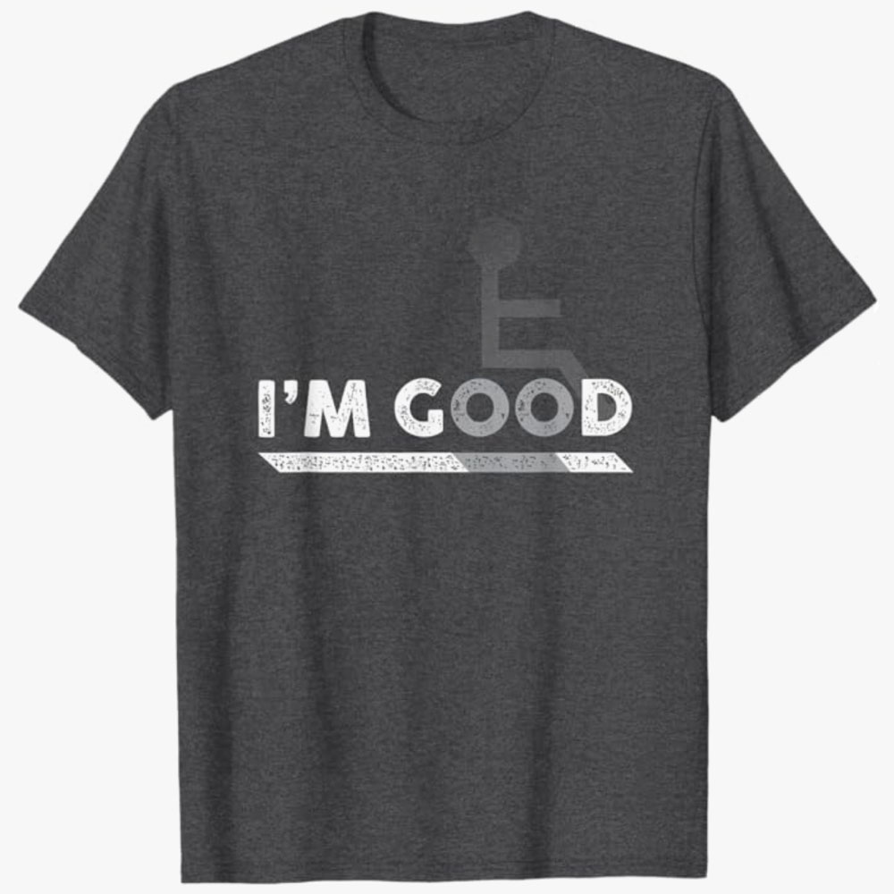 A dark gray T-shirt features the words “I’m Good” with a subtle wheelchair symbol integrated into the design. The image conveys self-acceptance, confidence, and reassurance that no explanation or justification is needed.