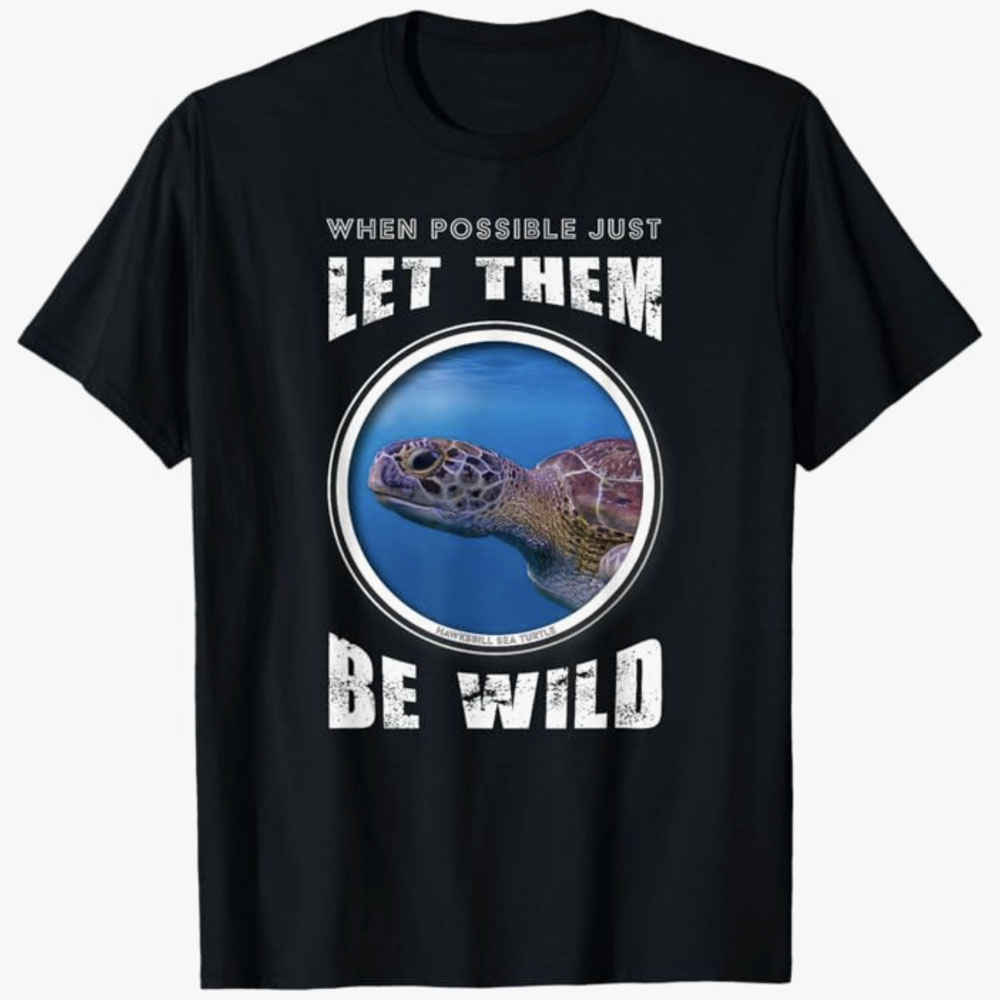 A black T-shirt shows a hawksbill sea turtle swimming inside a circular frame with the words “When possible just let them be wild.” The design encourages ocean conservation and respect for wildlife living freely in their natural habitats.