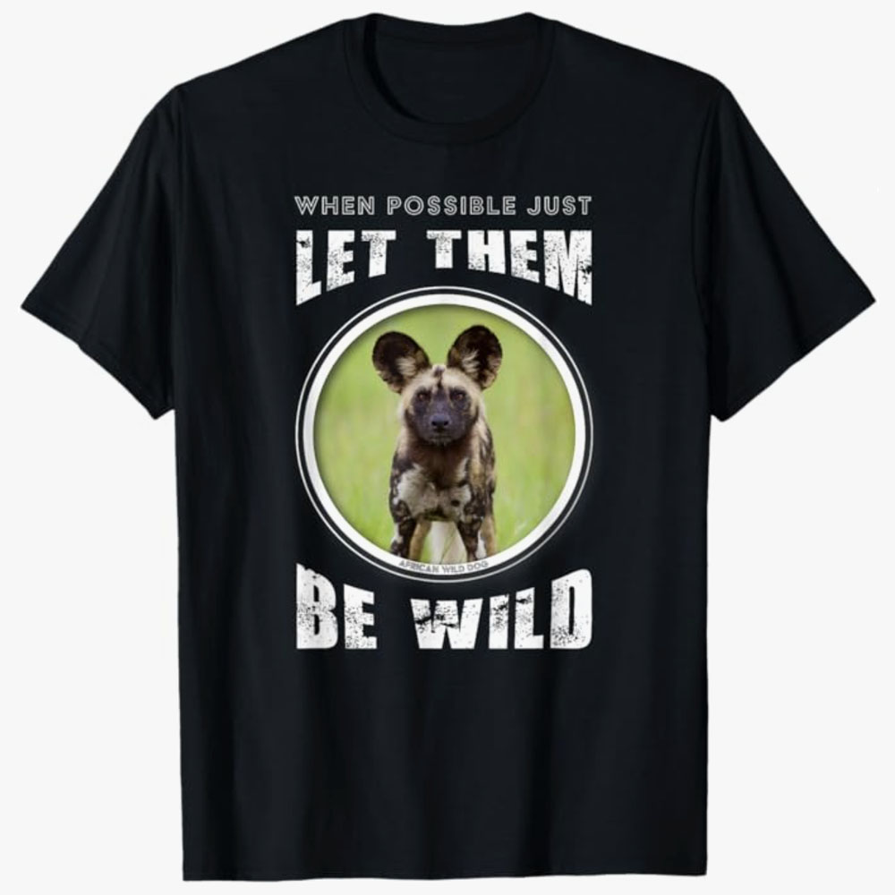 A black T-shirt features an African wild dog inside a circular frame with the words “When possible just let them be wild.” The design promotes wildlife conservation and respect for animals living freely in nature.