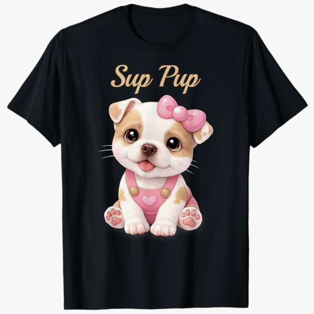 A black T-shirt features a cute cartoon puppy wearing a pink bow and overalls with the playful phrase Sup Pup, designed for dog lovers who enjoy adorable pet-themed humor.